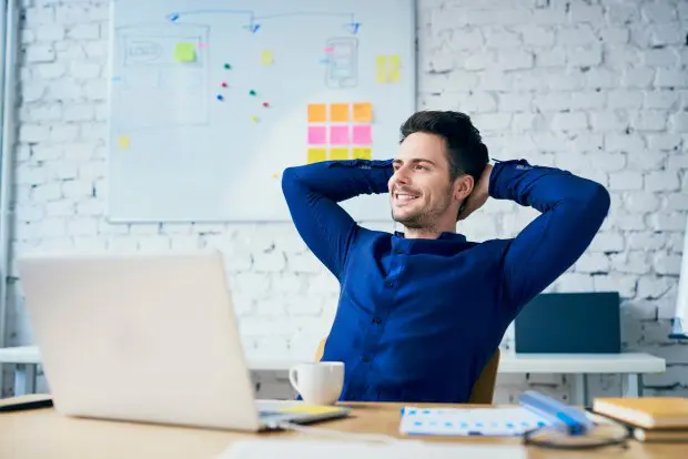 Satisfied young man in office looking away