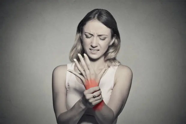 Young adult female that is holding her wrist that is in pain.