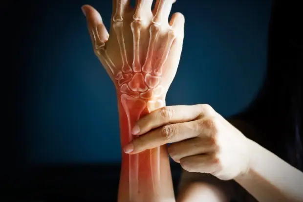 A close-up view of a person's wrist and hand that is experiencing pain.