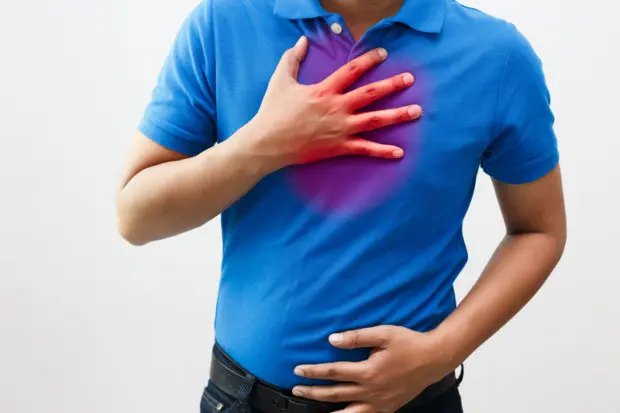 Close-up view of a man's torso and he is having heartburn pain.