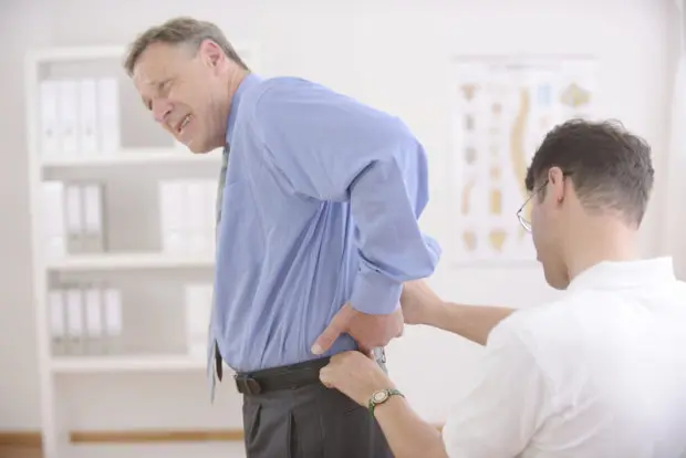 A man with lower back pain that is seeing a chiropractor for his care.