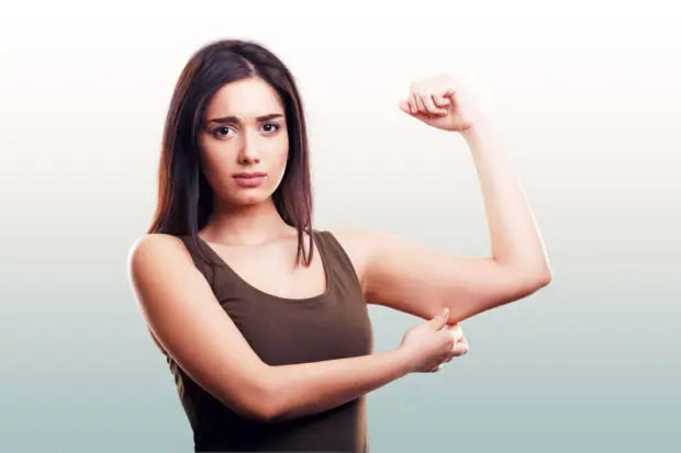 Woman that is flexing her bicep, but showing that her muscle is very weak.
