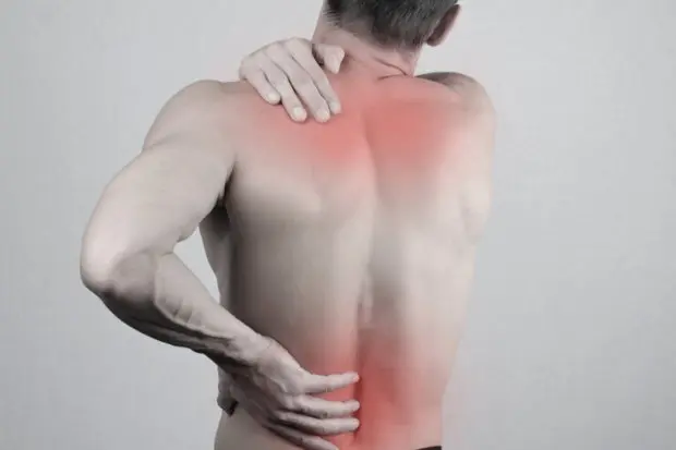 View of a man's back as he is holding areas in pain.