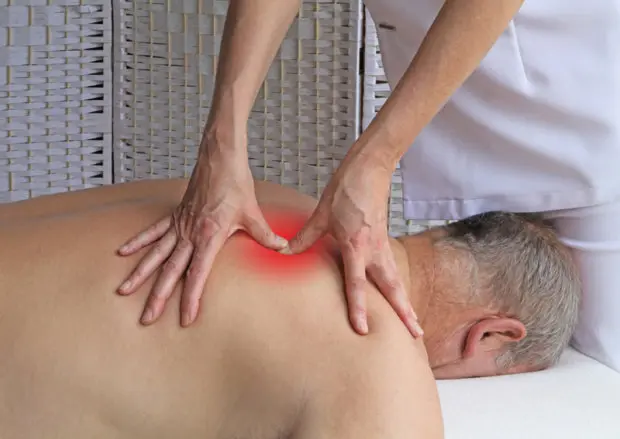 A man that is receiving trigger point therapy for a knot in his back, which is a trigger point.