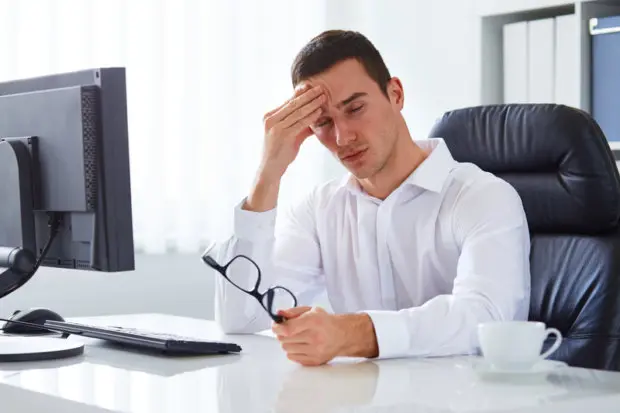 Young male that has taken his glasses off and is experiencing headache pain.