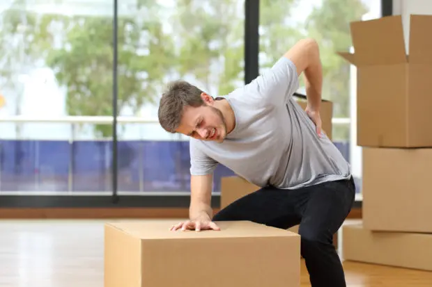 A man that is having severe back pain from lifting boxes wrong.