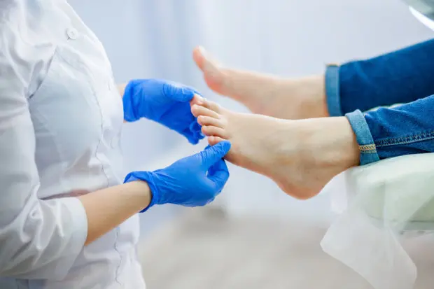 A close-up of a doctor examining a patient's feet.