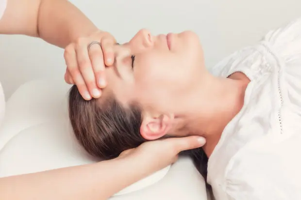 A close-up view of a patient with headache pain that is having a chiropractic adjustment on their head and neck.