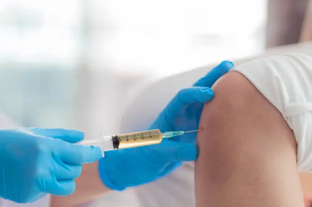 A close-up view of a patient receiving an injection in their knee for pain.