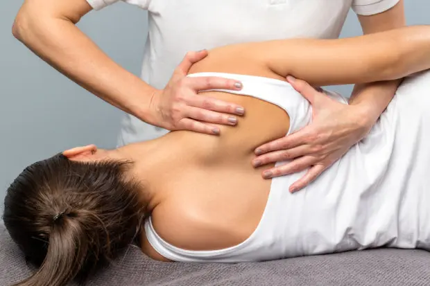 A close-up view of a female patient having her back adjusted by a chiropractor.