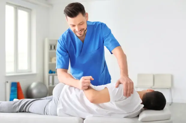 A chiropractic professional that is adjusting a male patient's back.