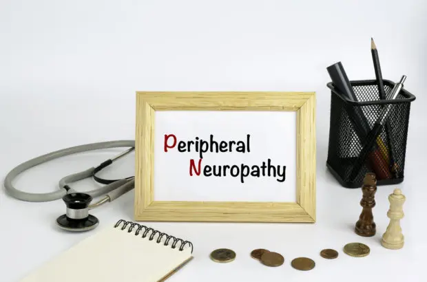 A framed photo that says "Peripheral Neuropathy" with items such as coins, a notepad, a stethoscope and other medical items surrounding the framed image.